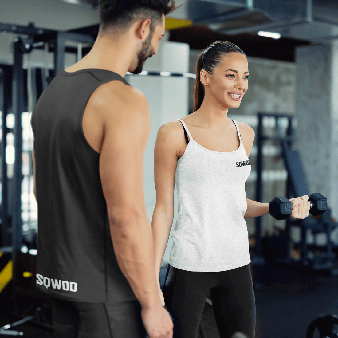 Personal trainer in Berlin assisting a woman with dumbbell exercises at a fitness studio.