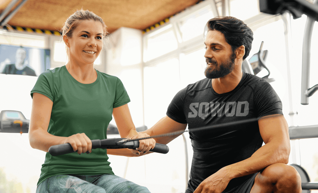 Personal trainer assisting a woman with rowing exercise in a fitness studio in Berlin.